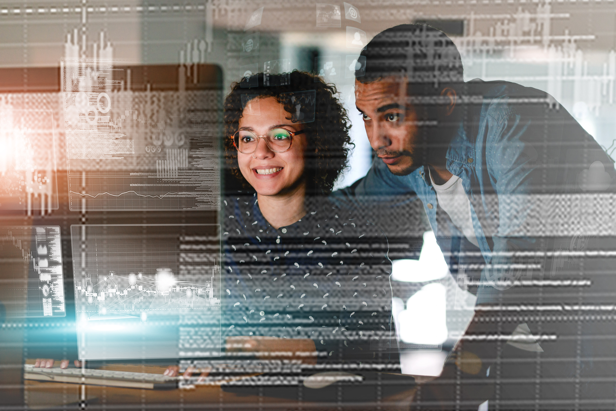 Two Programmers Collaborating with Futuristic Graphics Overlayed in Low Light Environment